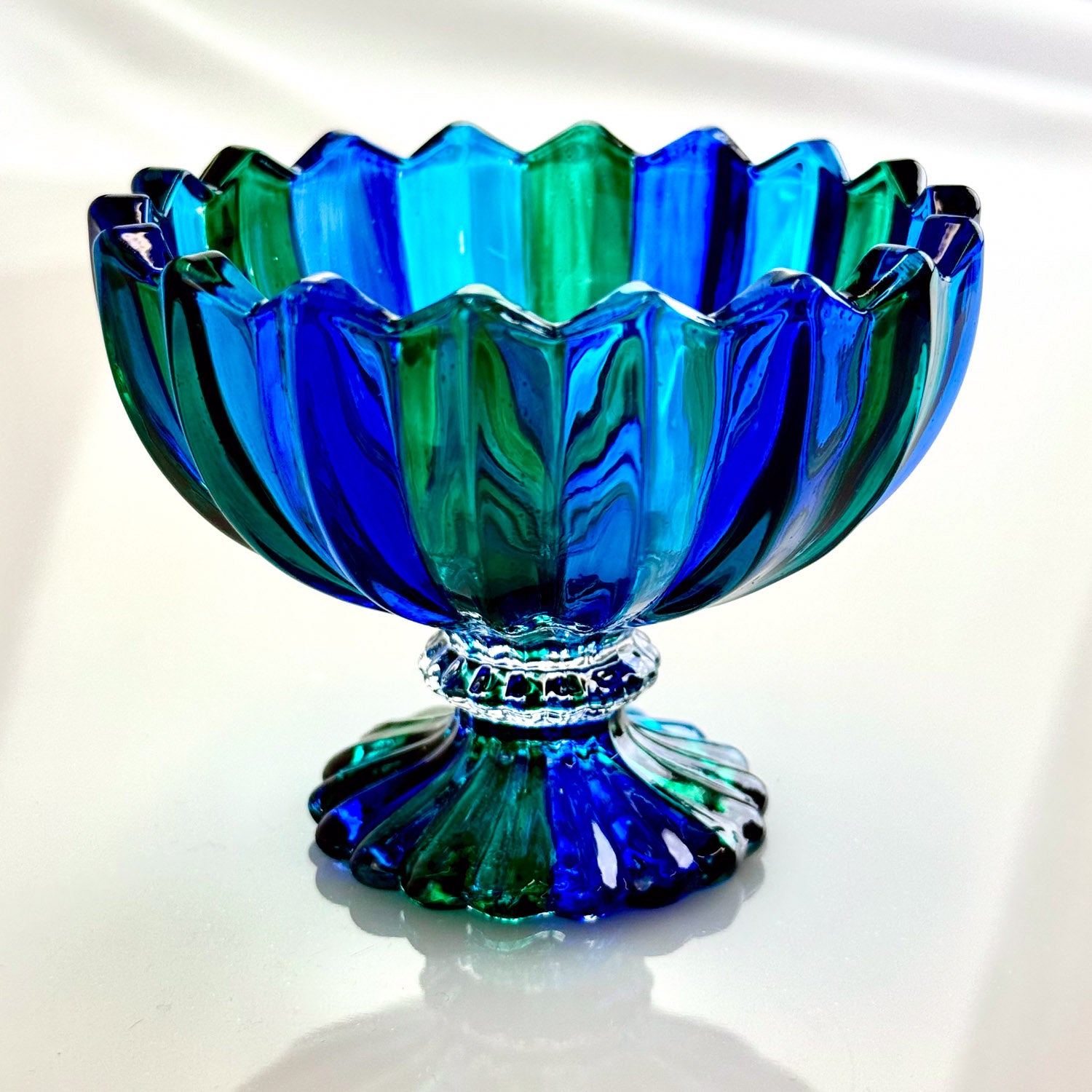 Blue and green glass bowl with textured design on a white background