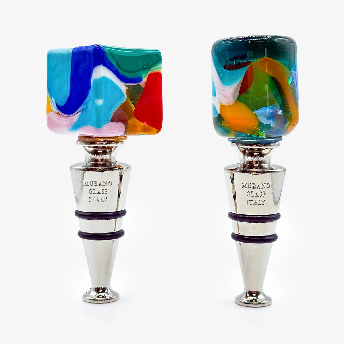 Two Murano glass wine stoppers on a white background. One stopper features a square top with a vibrant, multicolored fused glass design, while the other has a cylindrical top with a similar multicolored pattern.