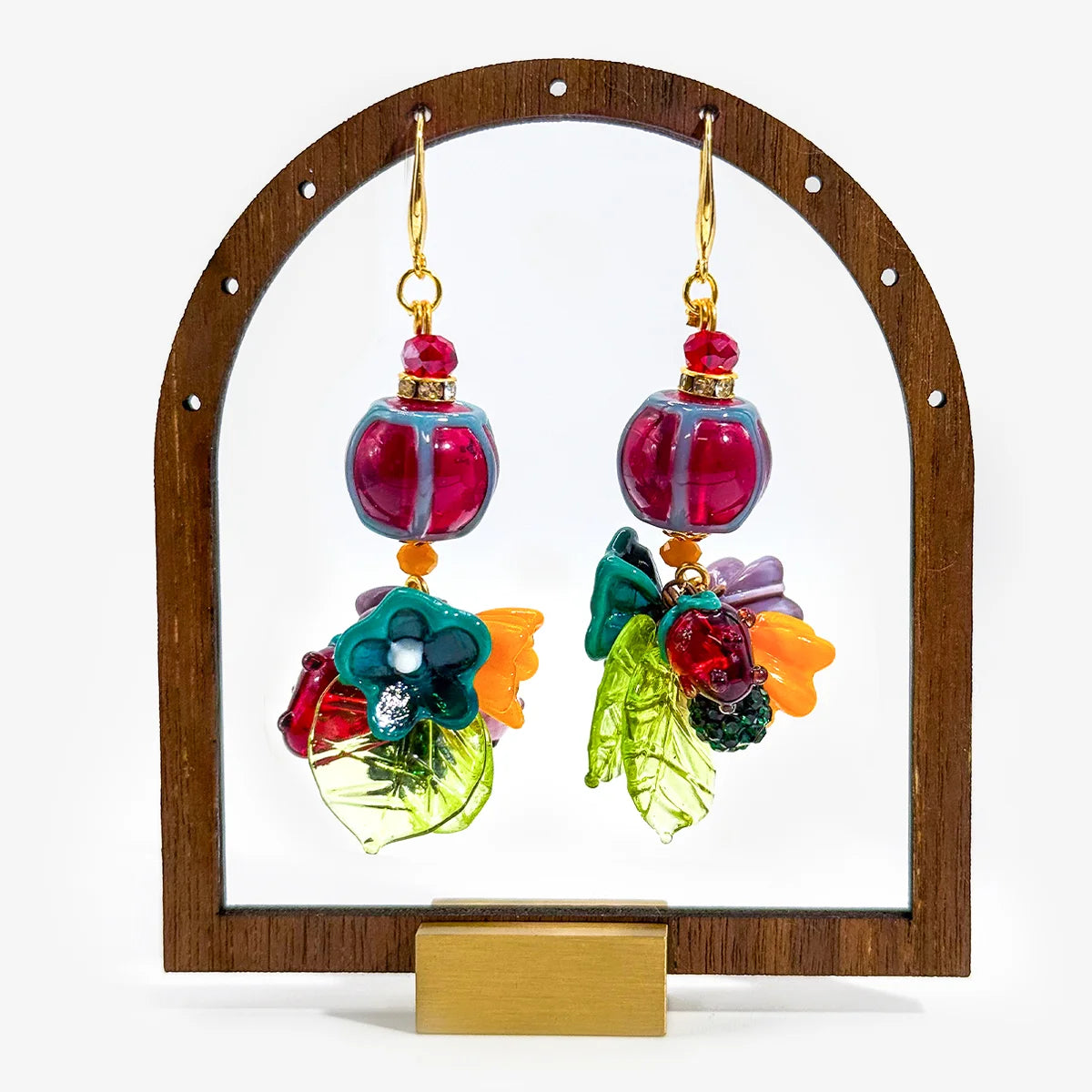 A handmade jewelry set featuring a beaded bracelet and matching drop earrings on a white background. The beads are primarily deep burgundy with red swirls, turquoise blue accents, and a purple mesh ribbon bow.