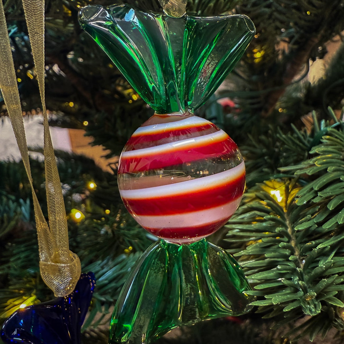 Decorative candy ornament with green, red, and white stripes on a Christmas tree.