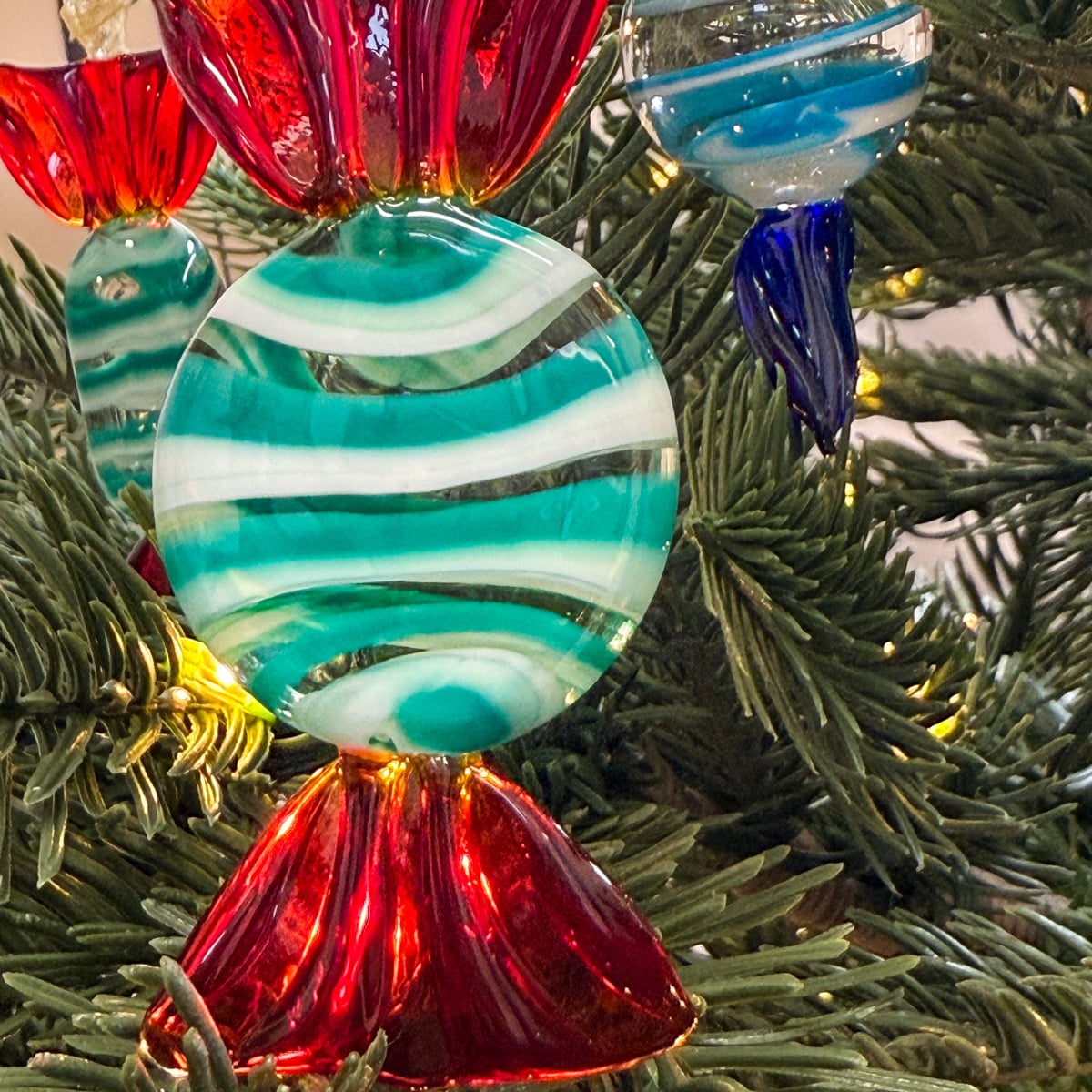 Colorful glass ornament with red, blue, and green swirls on a Christmas tree.