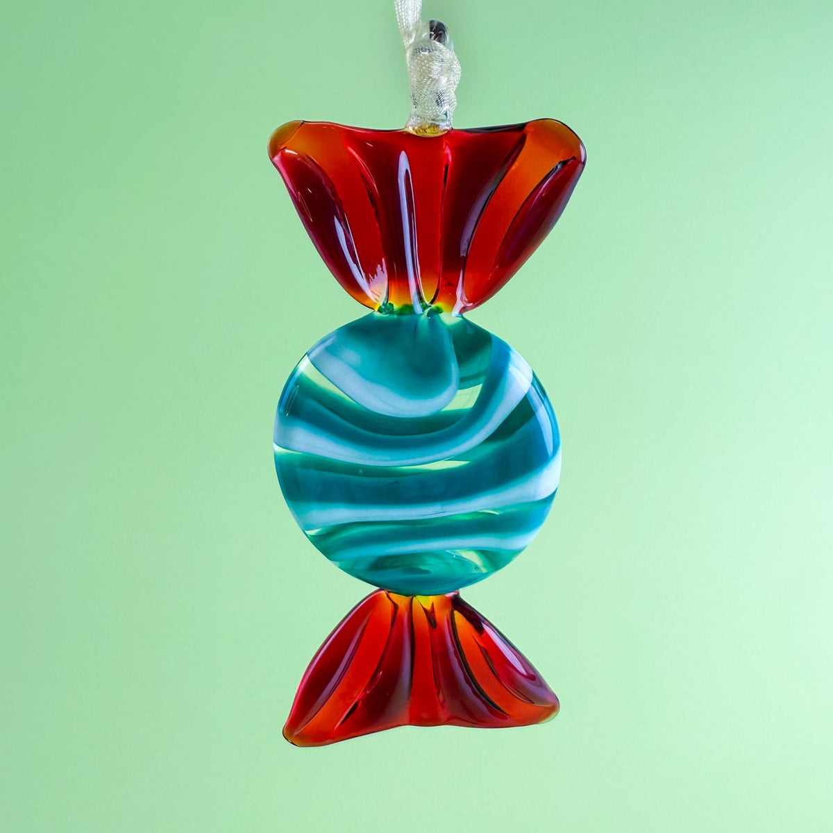 Colorful glass candy-shaped ornament on a green background