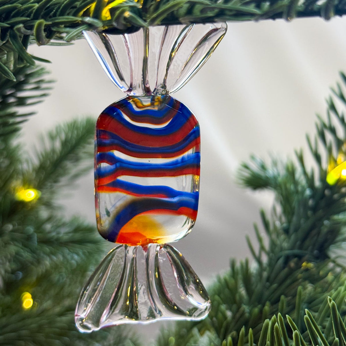 Colorful glass candy ornament hanging on a Christmas tree.