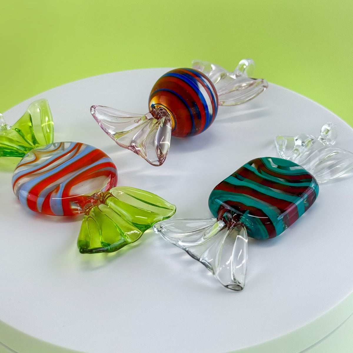 Colorful glass candies on a white plate with a green background