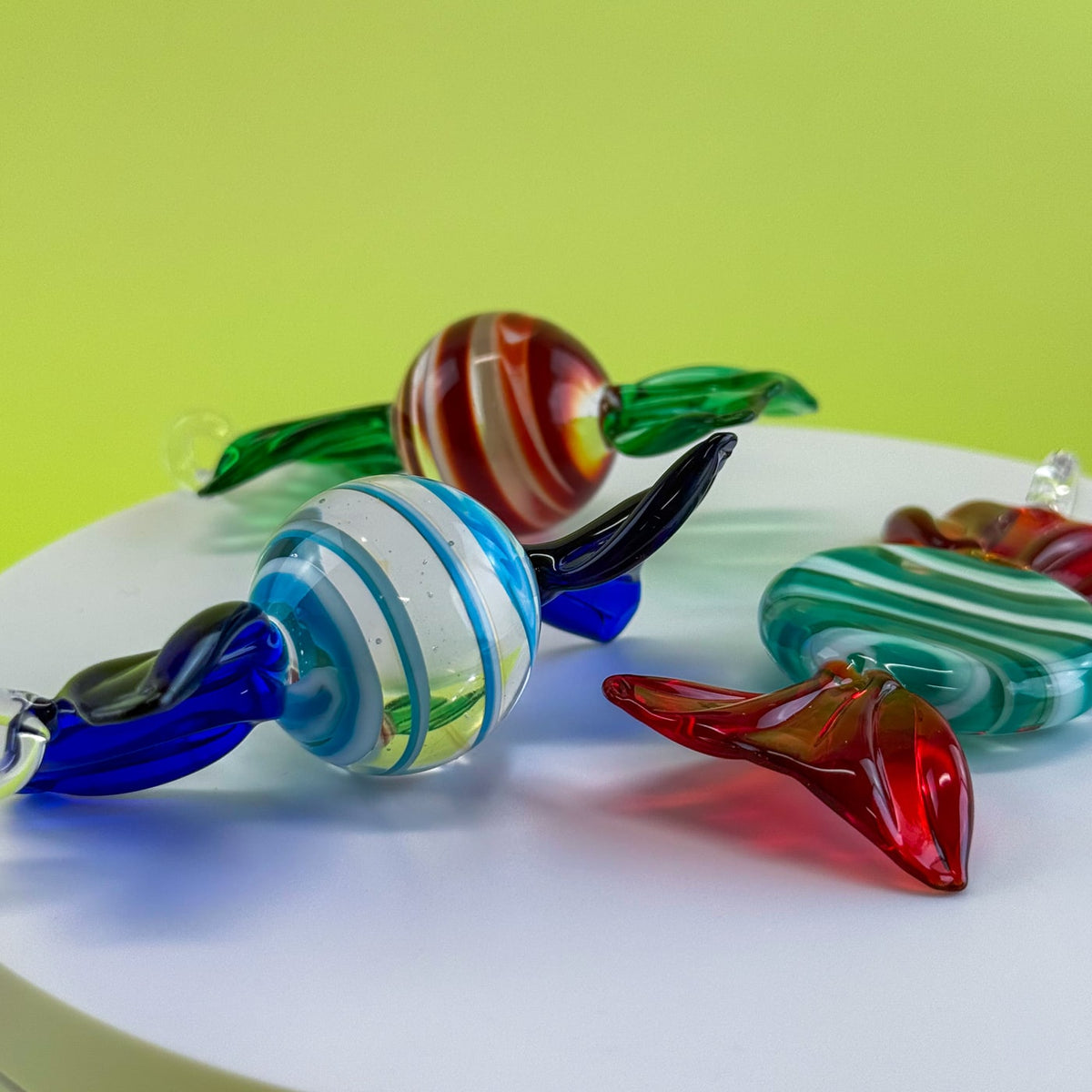 Colorful glass beads on a white plate with a green background