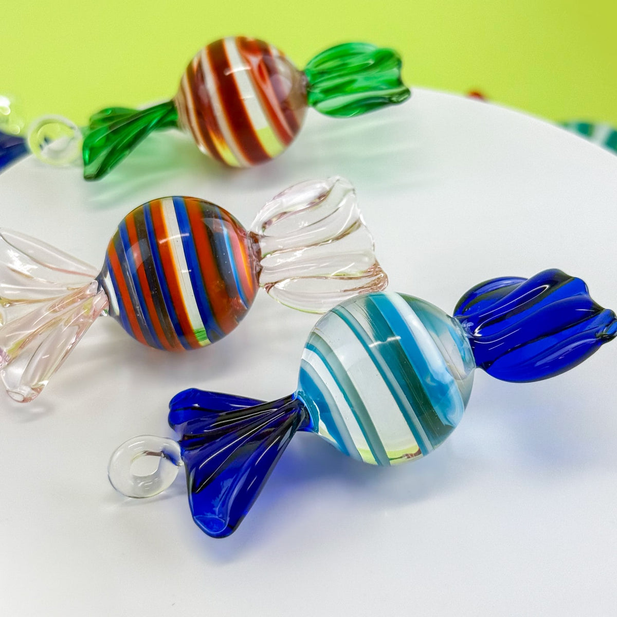 Colorful glass candies on a white plate with a green background