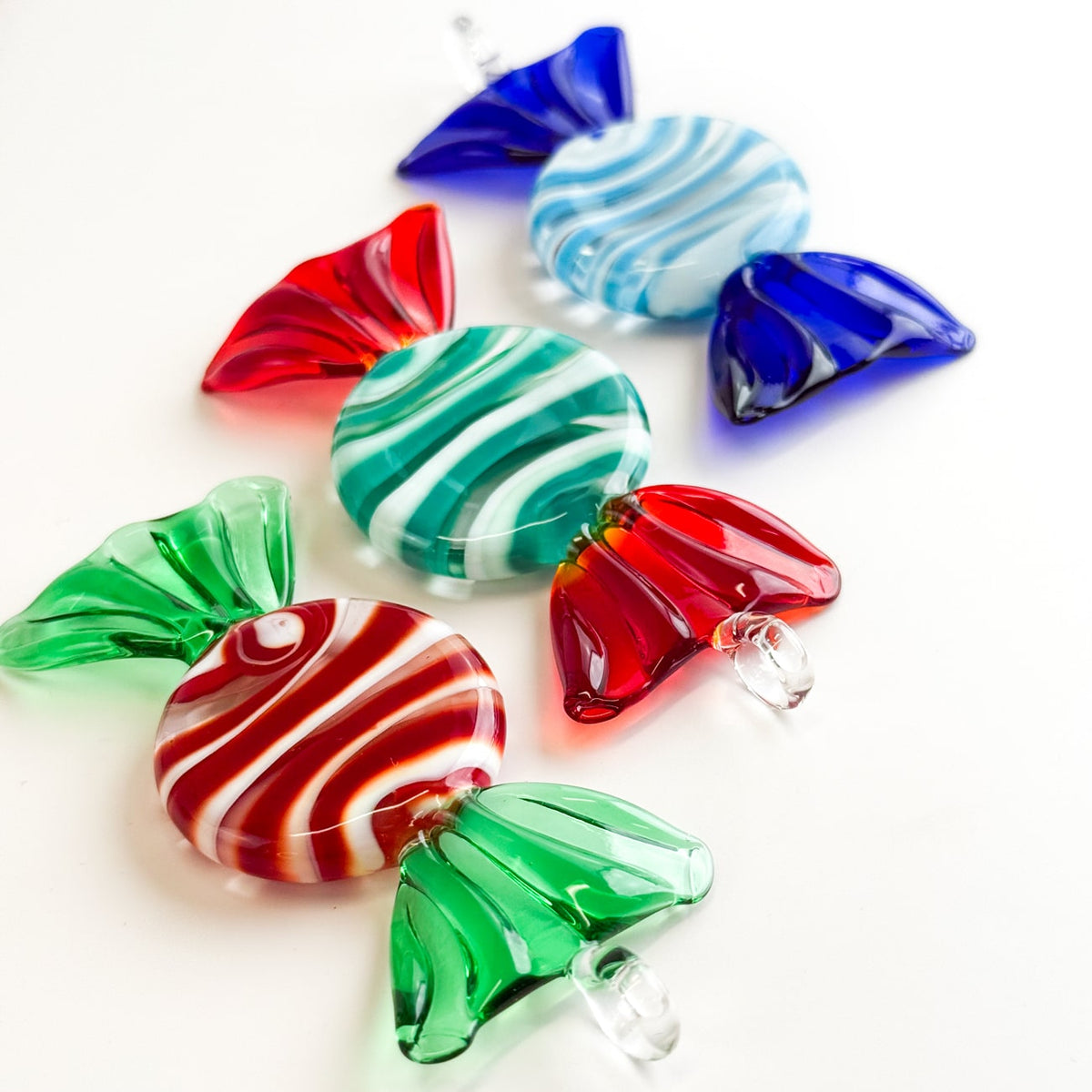 Colorful glass candy-shaped ornaments on a white background