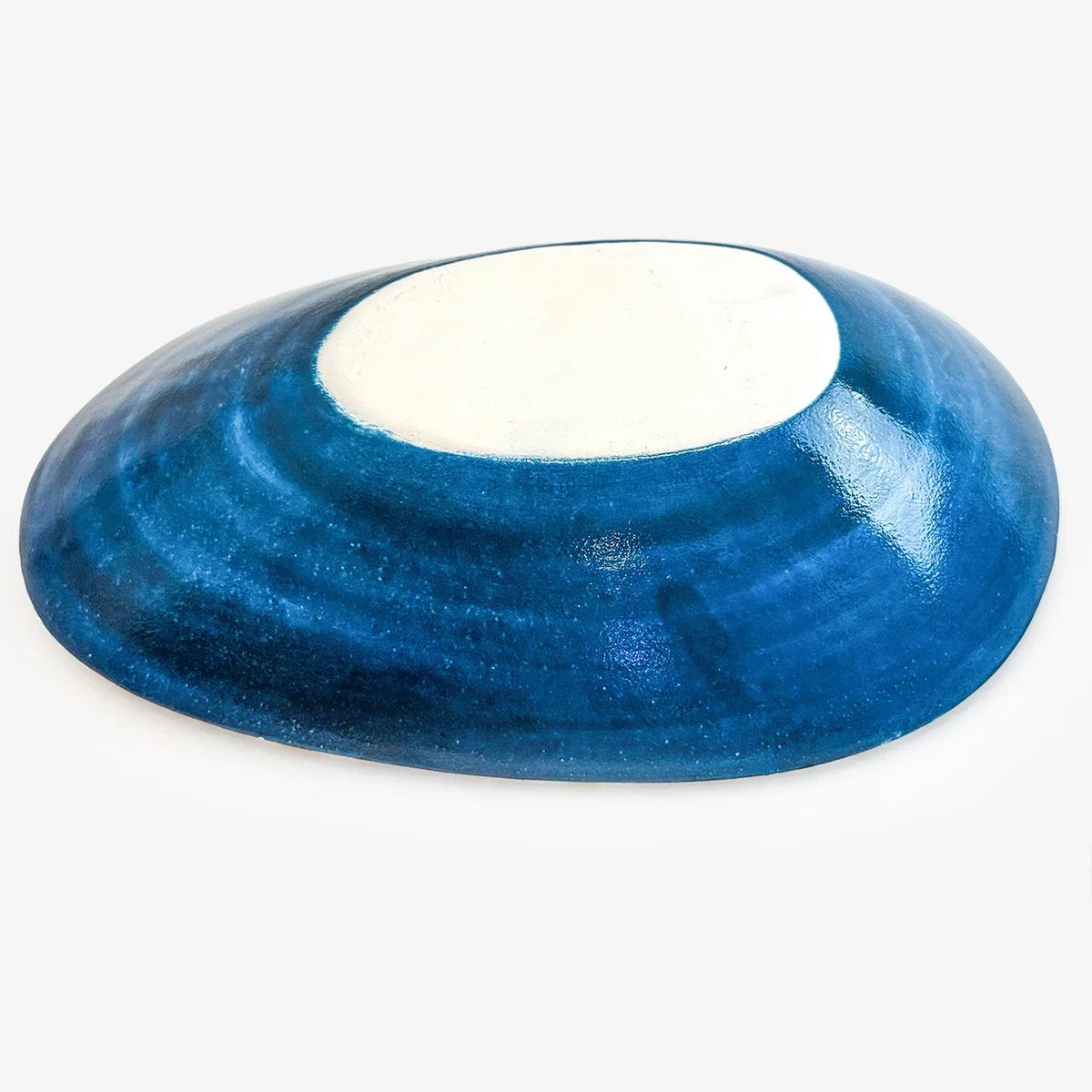 A small, rounded ceramic dish with a deep blue glazed exterior and a contrasting white interior, shown on a plain light gray background.