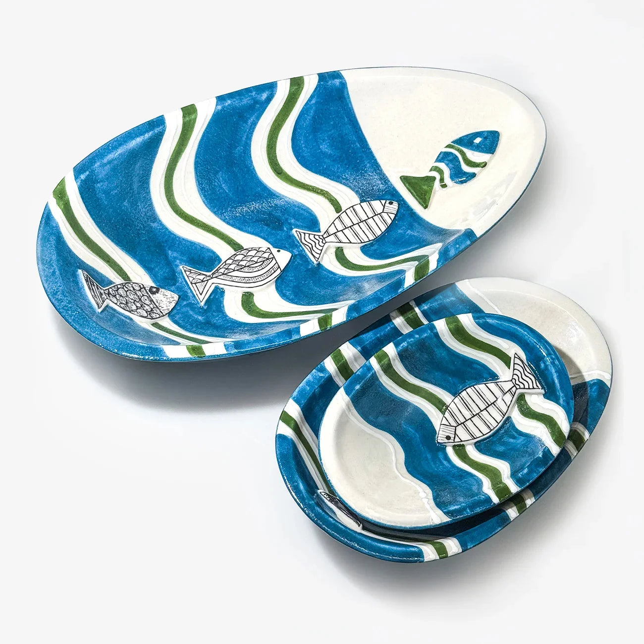 A set of ceramic serving platters with a blue and green wavy pattern and white fish illustrations, shown on a clean white background.