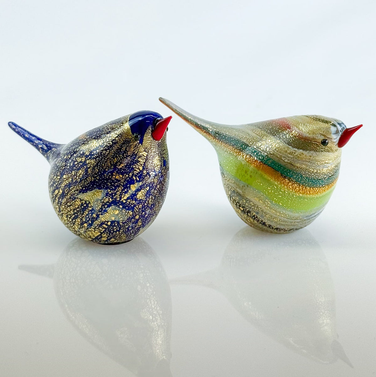 Two colorful glass bird figurines on a white background