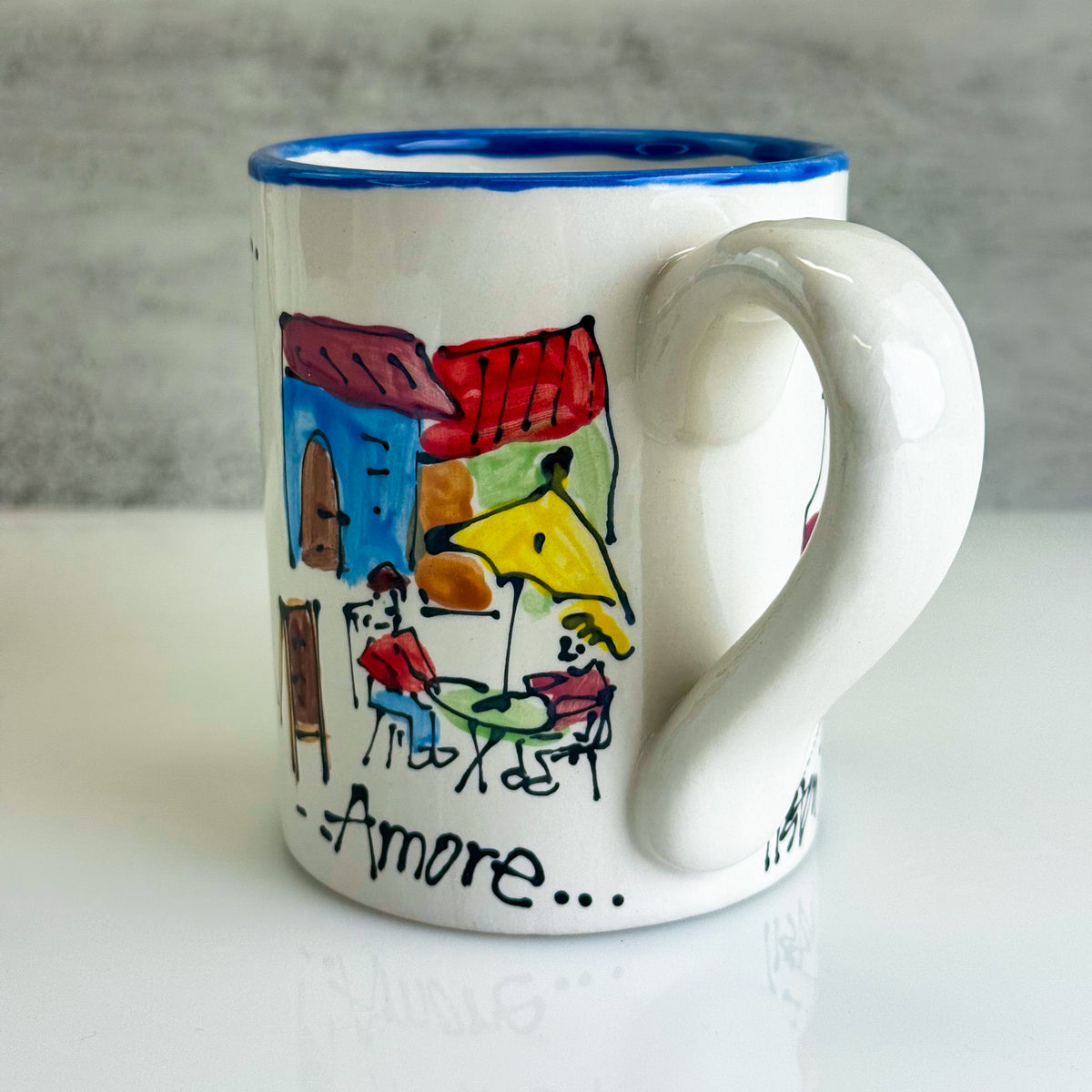 White mug with colorful artwork and 'Amore' text on a gray background