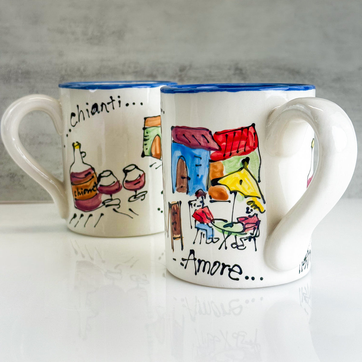 Two ceramic mugs with artistic designs and text on a neutral background