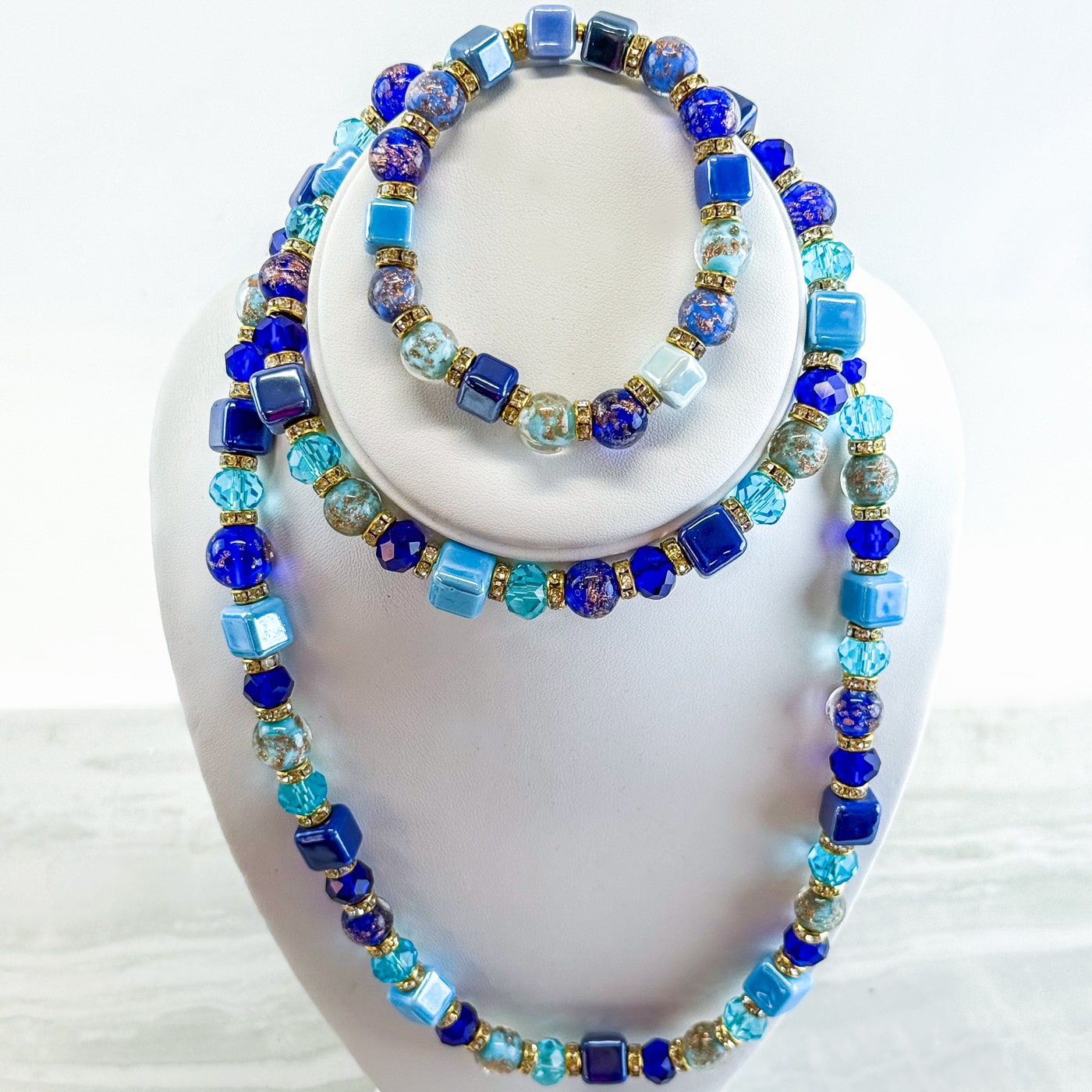 Blue beaded jewelry set including necklace and bracelet by DZ, featuring colorful beads in a stylish design.