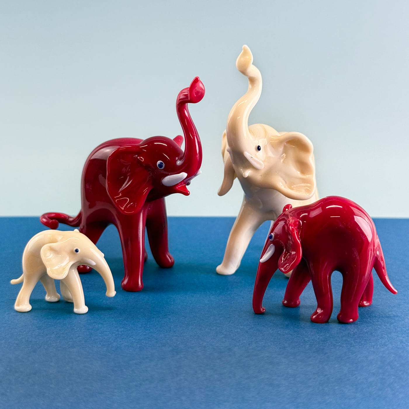 Set of three handcrafted Murano glass elephant figurines in ivory, showcasing detailed craftsmanship and Italian artistry.