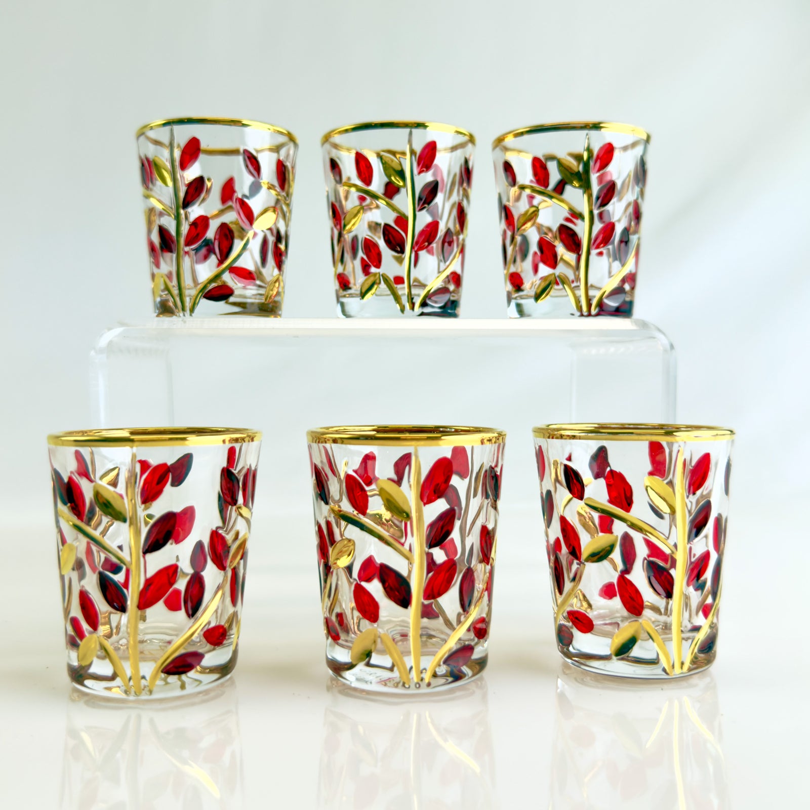 Set of 6 DZ Flowervine shot glasses in red, platinum, and gold with elegant designs, perfect for festive or casual occasions.
