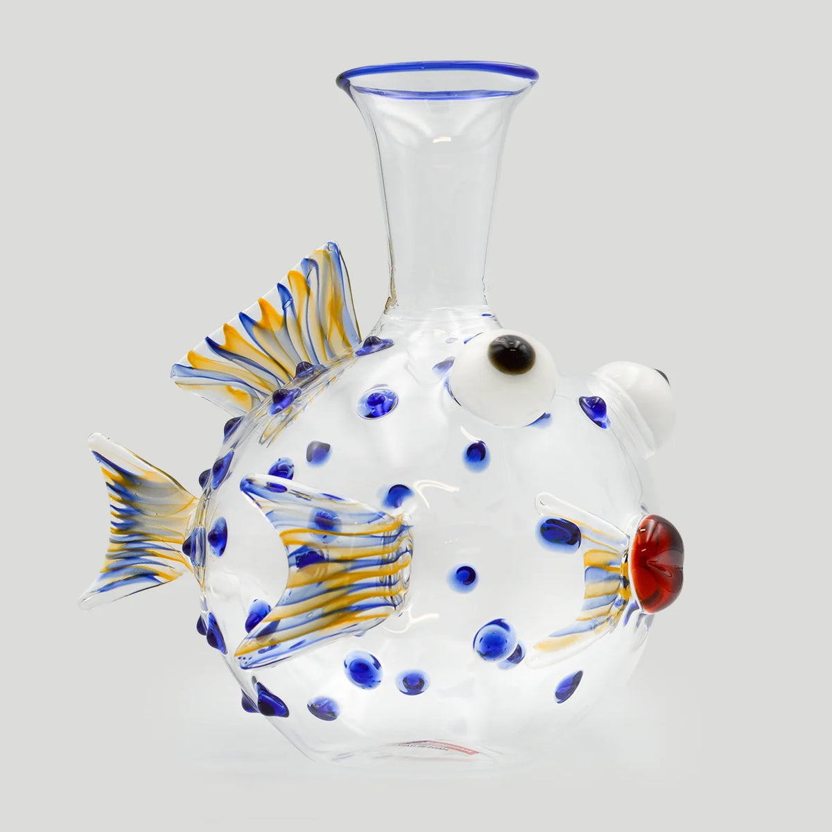A large fish-shaped glass decanter decorated with blue and yellow striped details, blue glass dots, shown on a light gray background.