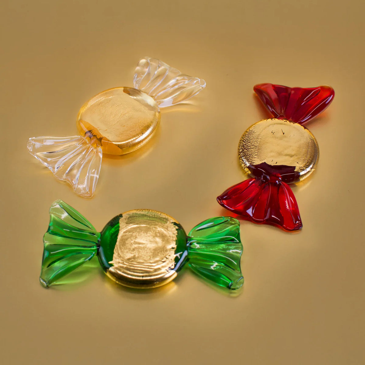 Set of five gold Murano glass candy-shaped artificial food pieces with shiny, reflective surfaces, crafted for decorative display.