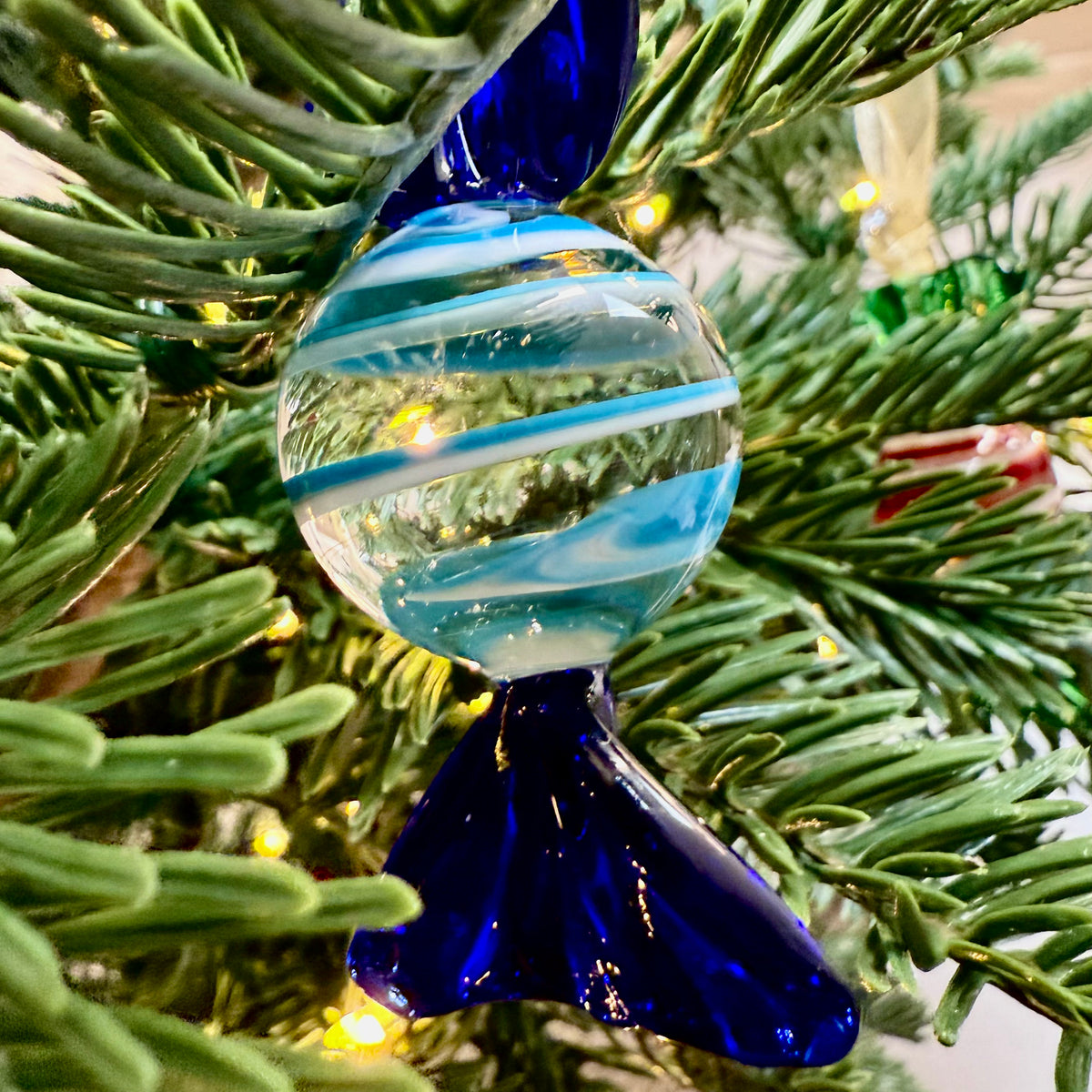 Blue and white striped glass ornament on a Christmas tree