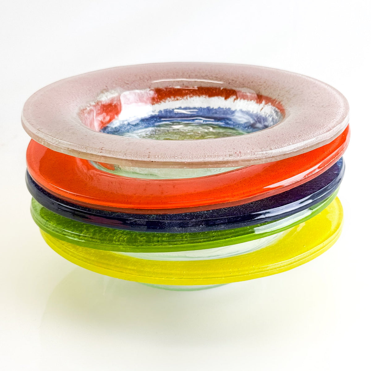 Stack of colorful glass bowls on a white background