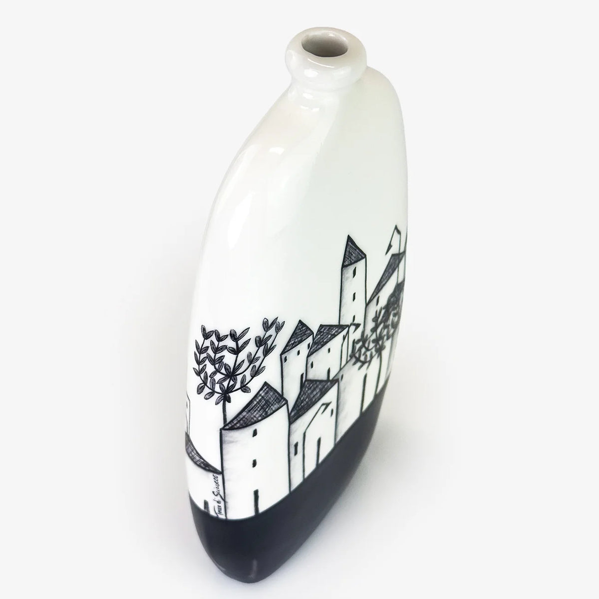 A white ceramic bottle with a black hand-painted village scene and a solid black base, shown on a clean white background.