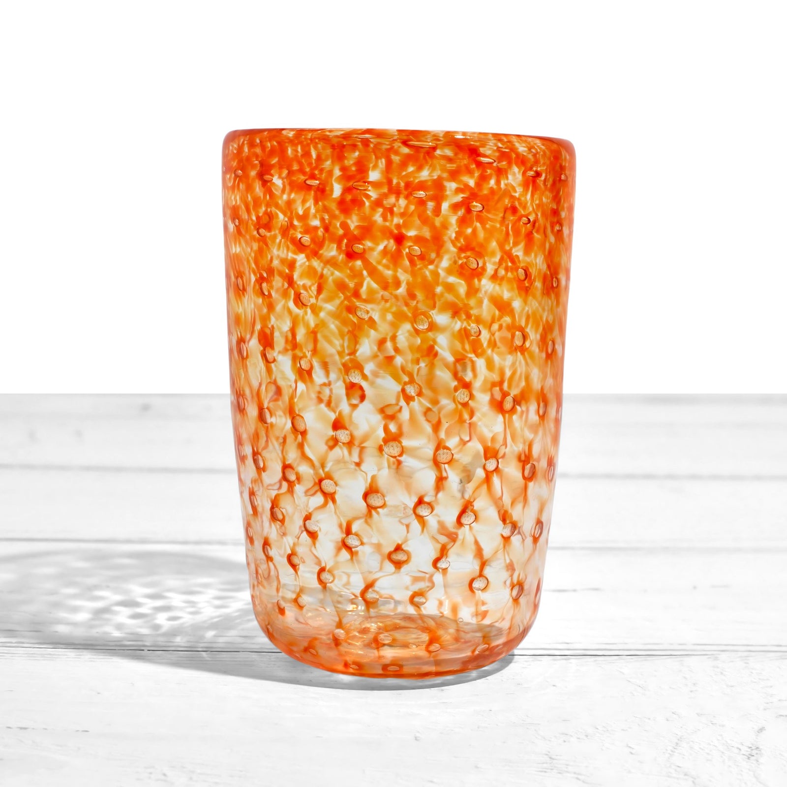 Colorful Ecco Murano tumbler glasses with orange, blue, violet, and lime hues, made in Italy, displayed on a neutral background.