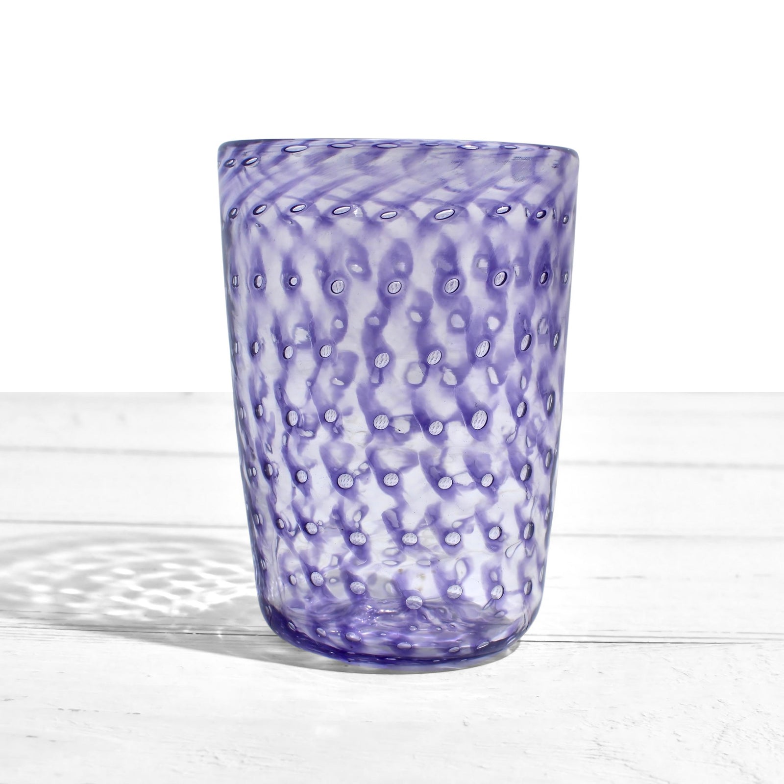 Colorful Ecco Murano tumbler glasses with orange, blue, violet, and lime hues, made in Italy, displayed on a neutral background.