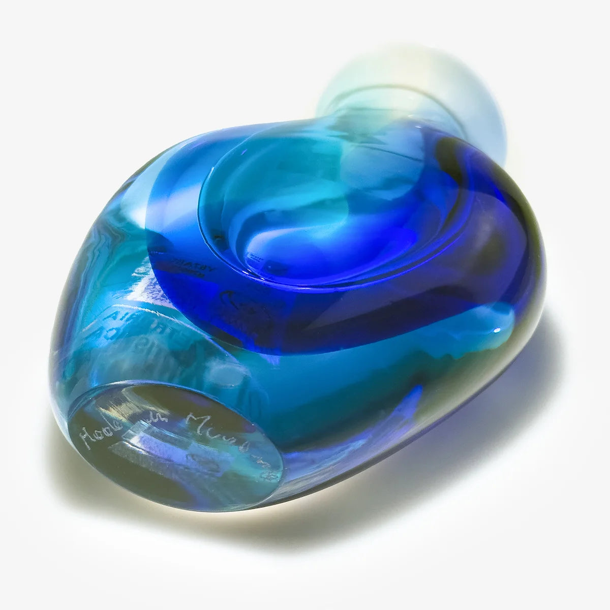 A hand-blown glass bottle with a rounded, organic shape, featuring a marbled pattern of vibrant blue, deep cobalt, and translucent white. The bottle is photographed on a clean white background with a soft shadow.