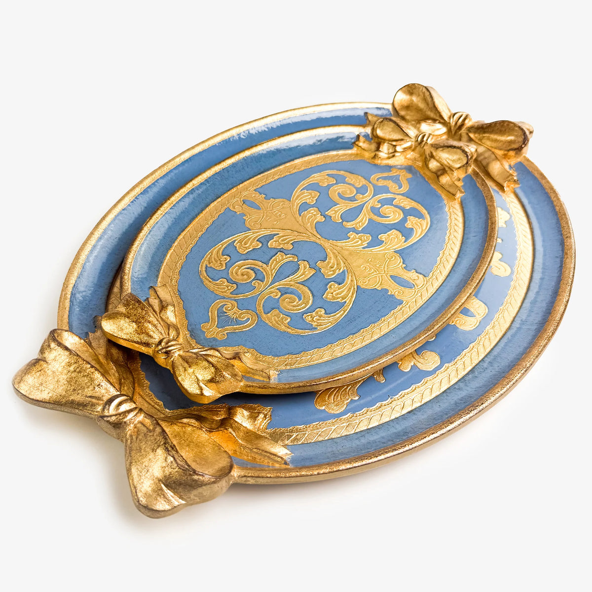 Two carved oval, dusty blue and gold Florentine trays with a bow detail. A medium sized tray is set inside a large tray.
