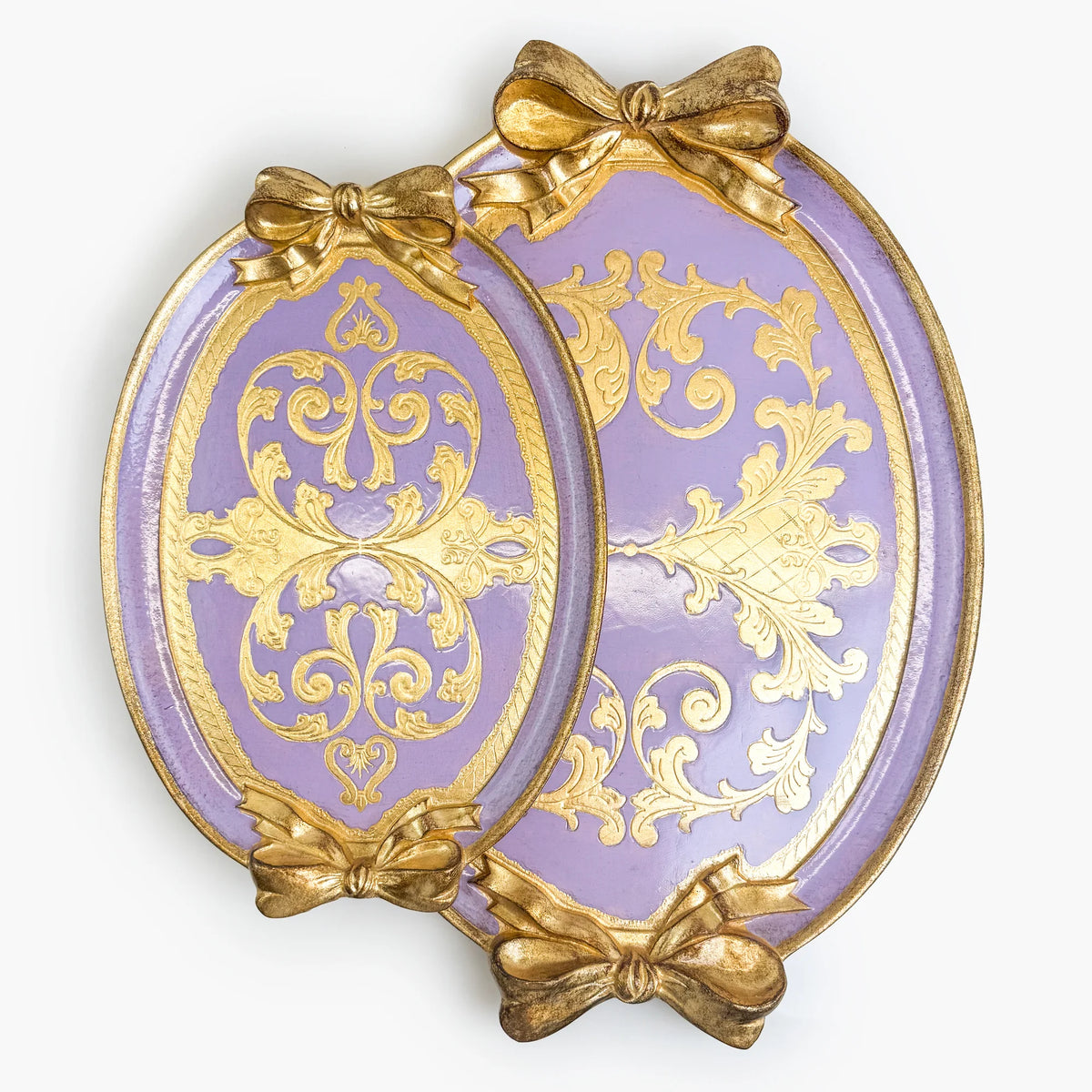 Two carved oval, lilac and gold Florentine bow trays with a bow detail, side by side.