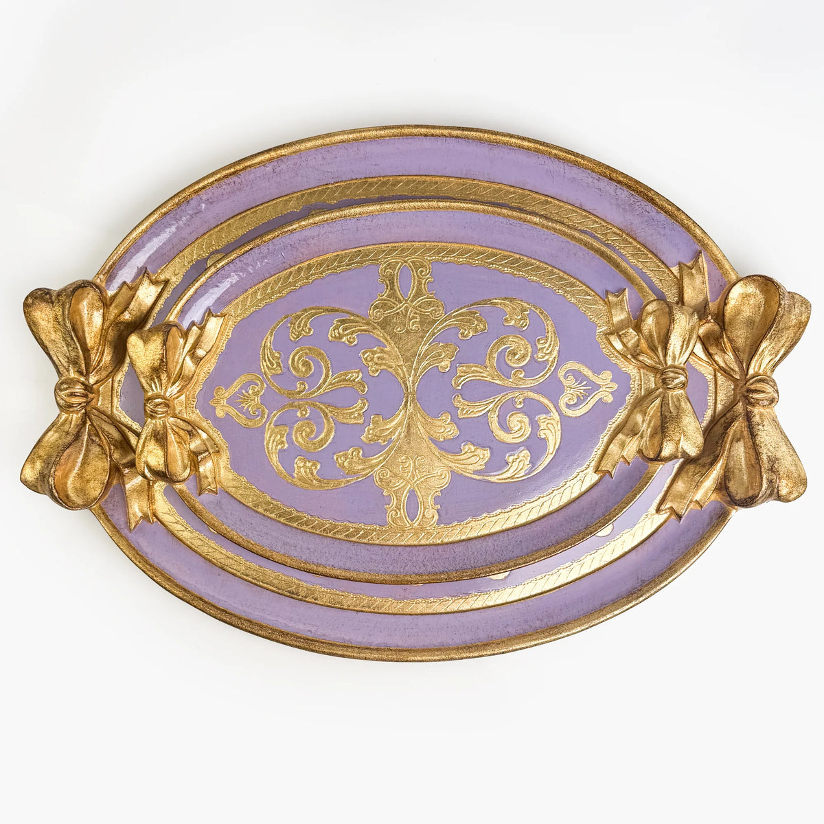 Two carved oval, lilac and gold Florentine bow trays, one medium tray set inside a large tray.