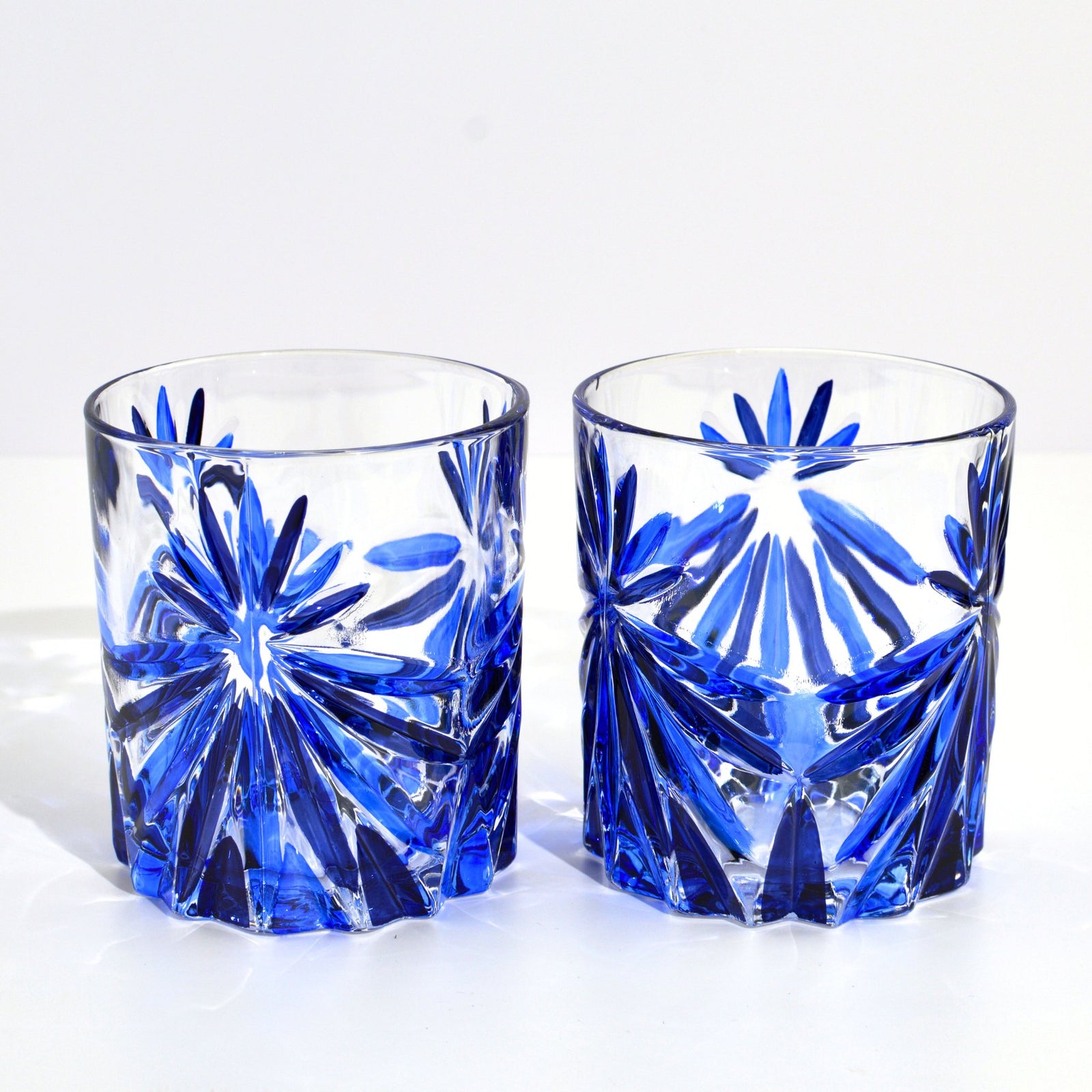 DZ Starburst short drink glasses, hand-painted Italian crystal tumblers in vibrant sapphire blue, ideal for stylish beverages.
