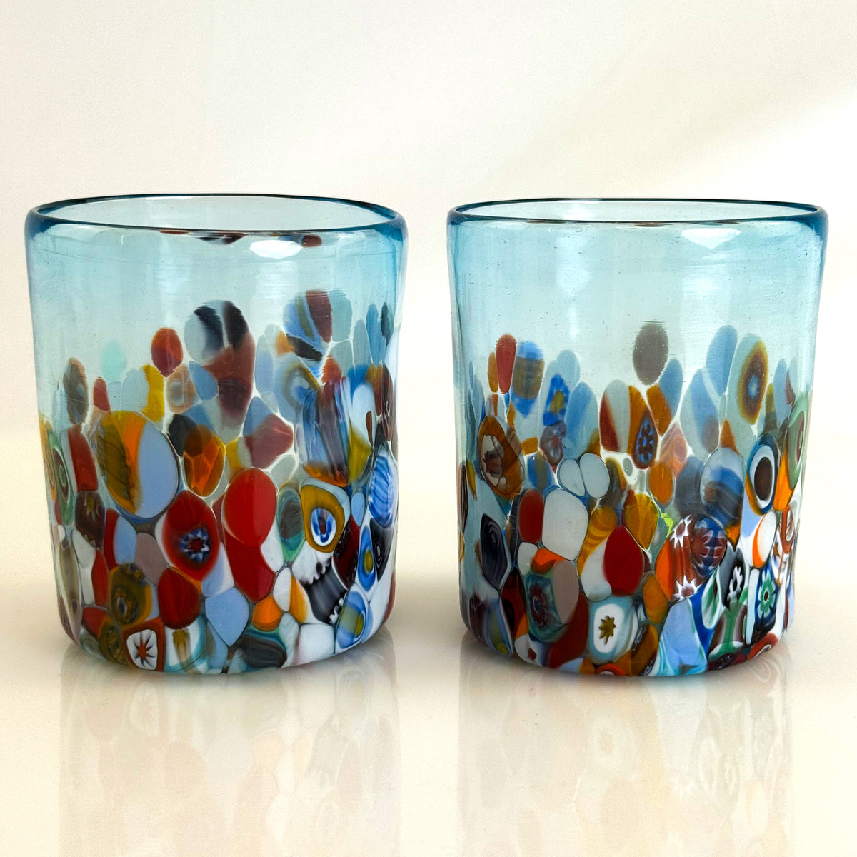 Two colorful glass tumblers with floral patterns on a white background