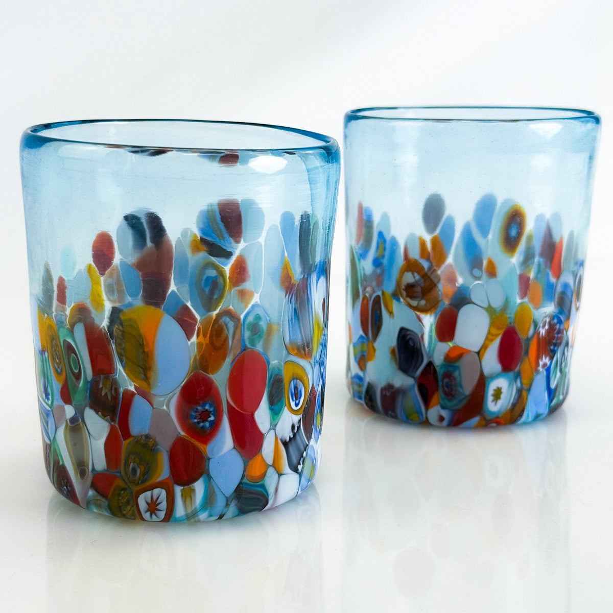 Two colorful glass tumblers with a mosaic design on a white background