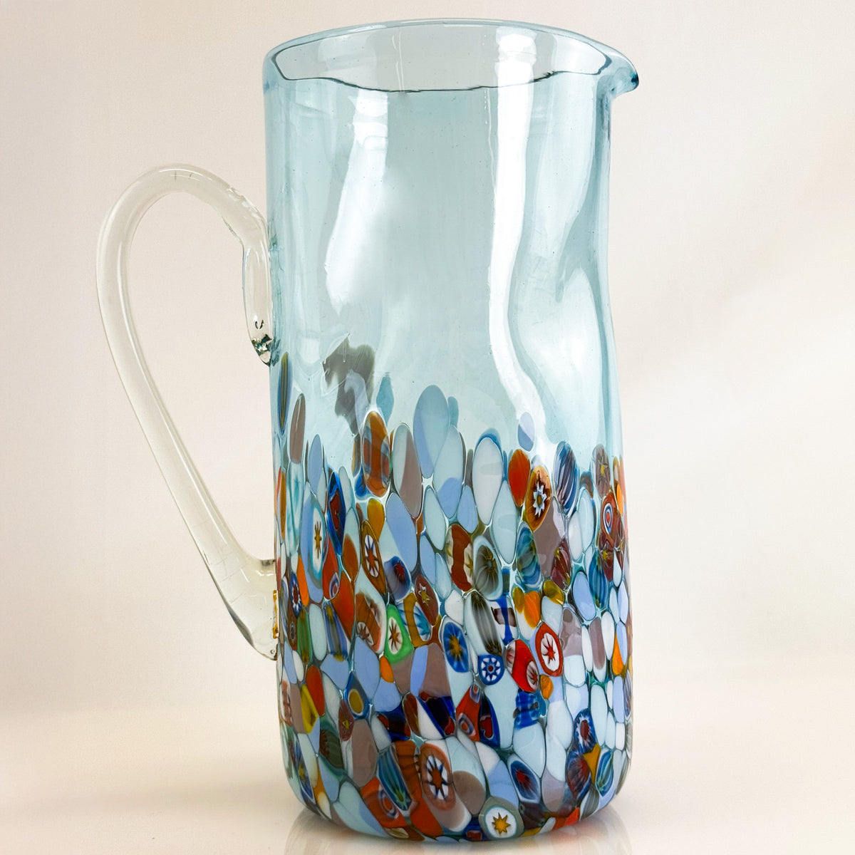 Glass pitcher with colorful mosaic pattern on a light background