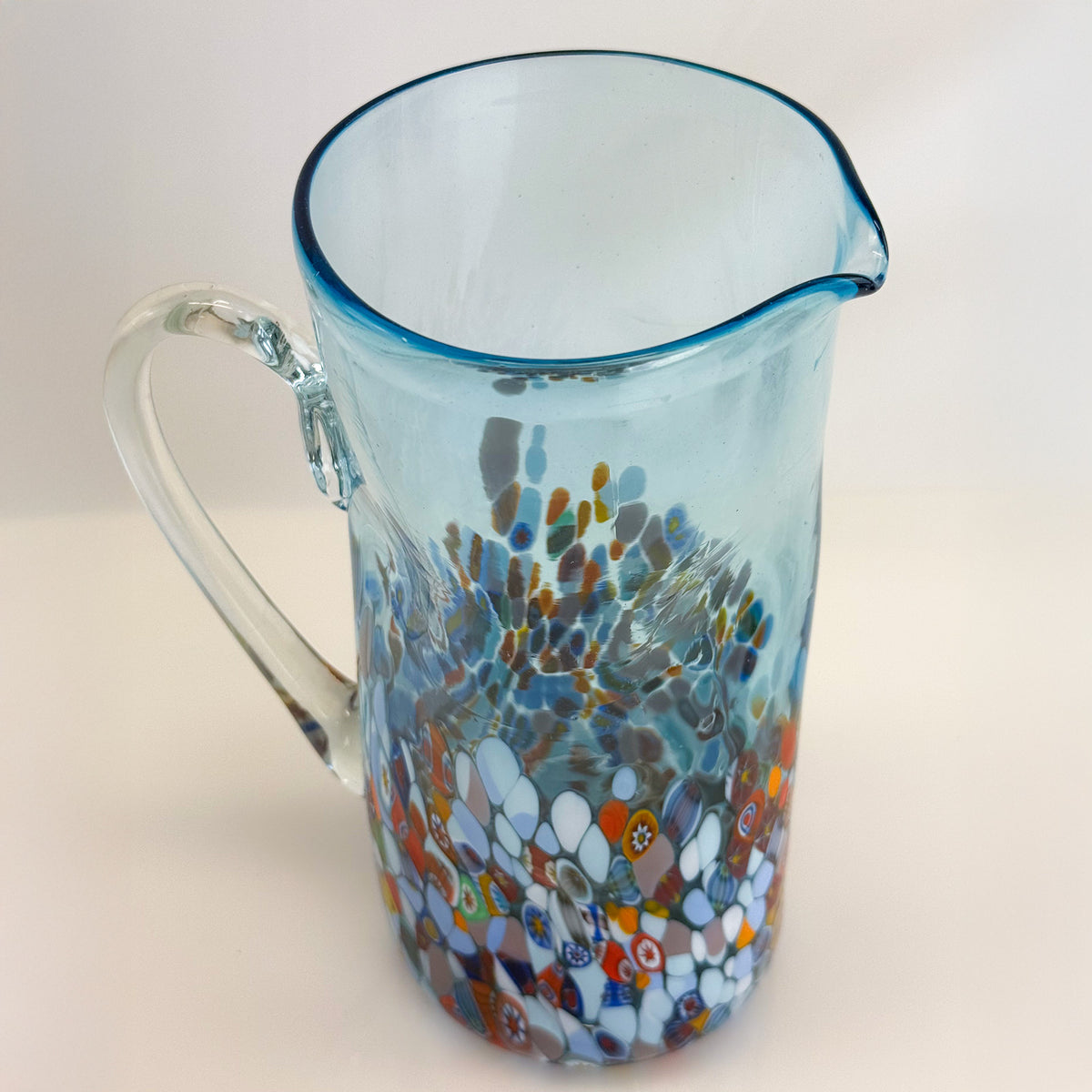 Glass pitcher with a colorful, marbled design on a white background