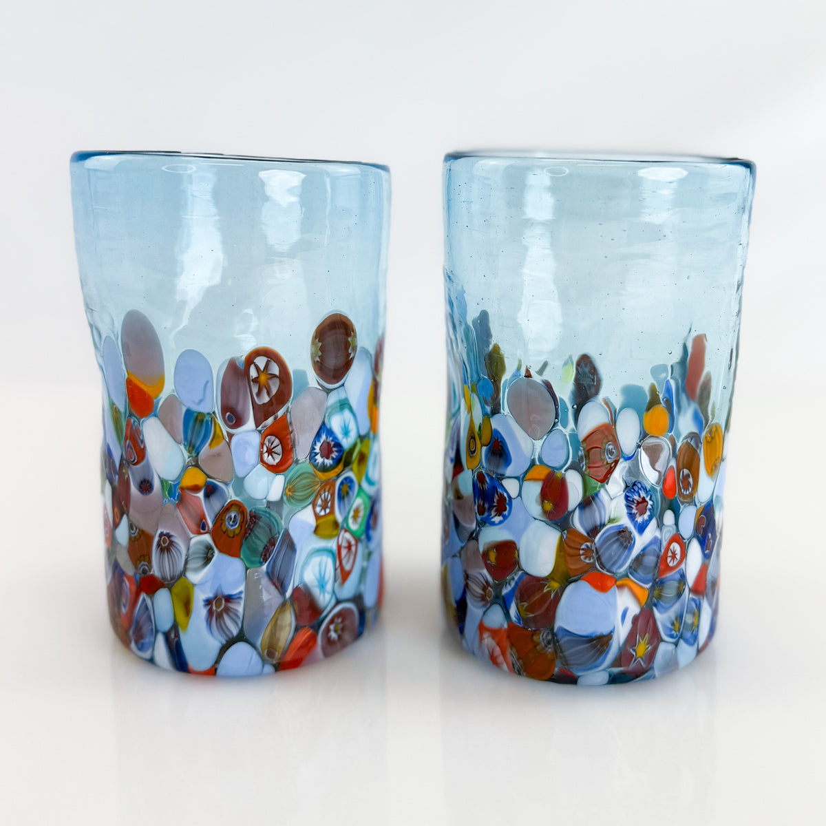 Two colorful glass tumblers with mosaic designs on a white background