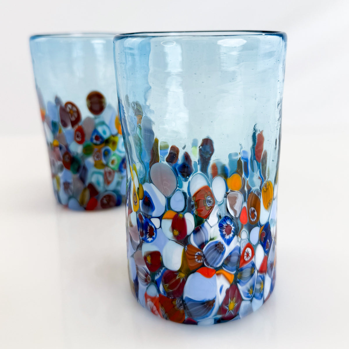 Two colorful glass tumblers with a pattern of multicolored circles on a white background