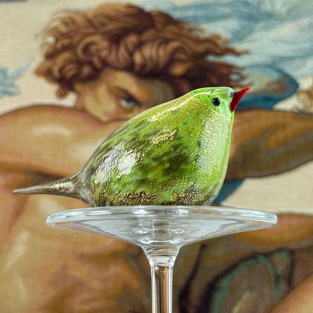 Lime green Murano glass Chirpie bird figurine with 24k gold accents, handcrafted by My Italian Decor, displayed on a tapestry background.