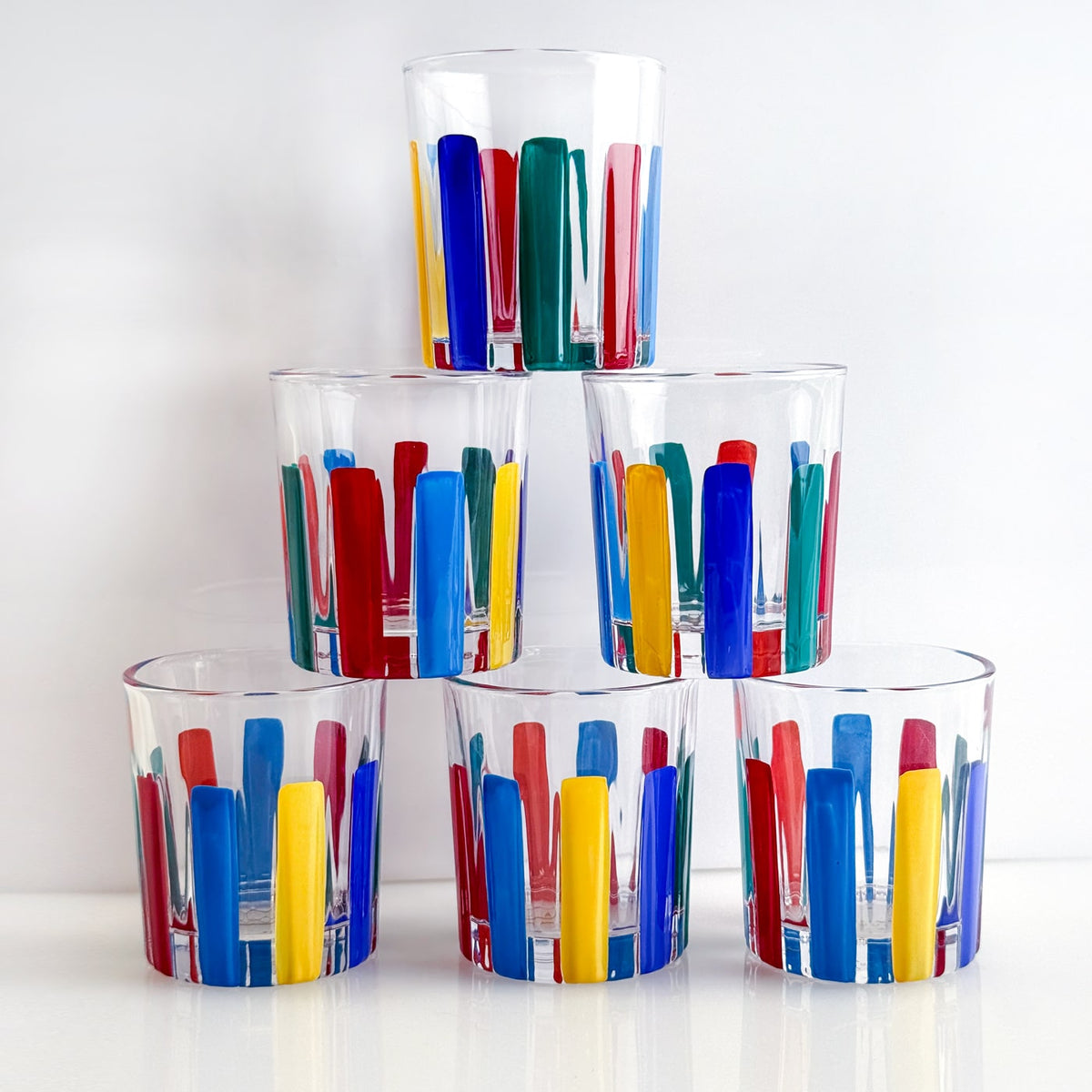 Set of colorful glass tumblers stacked on a white background