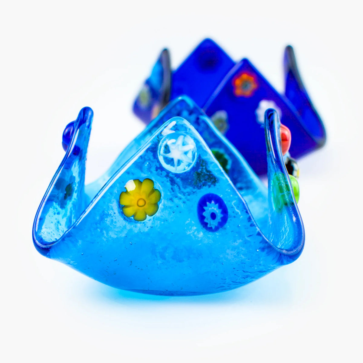 Colorful Murano glass Millefiori candle votive holder with intricate patterns, made in Italy, resting on a decorative tray.