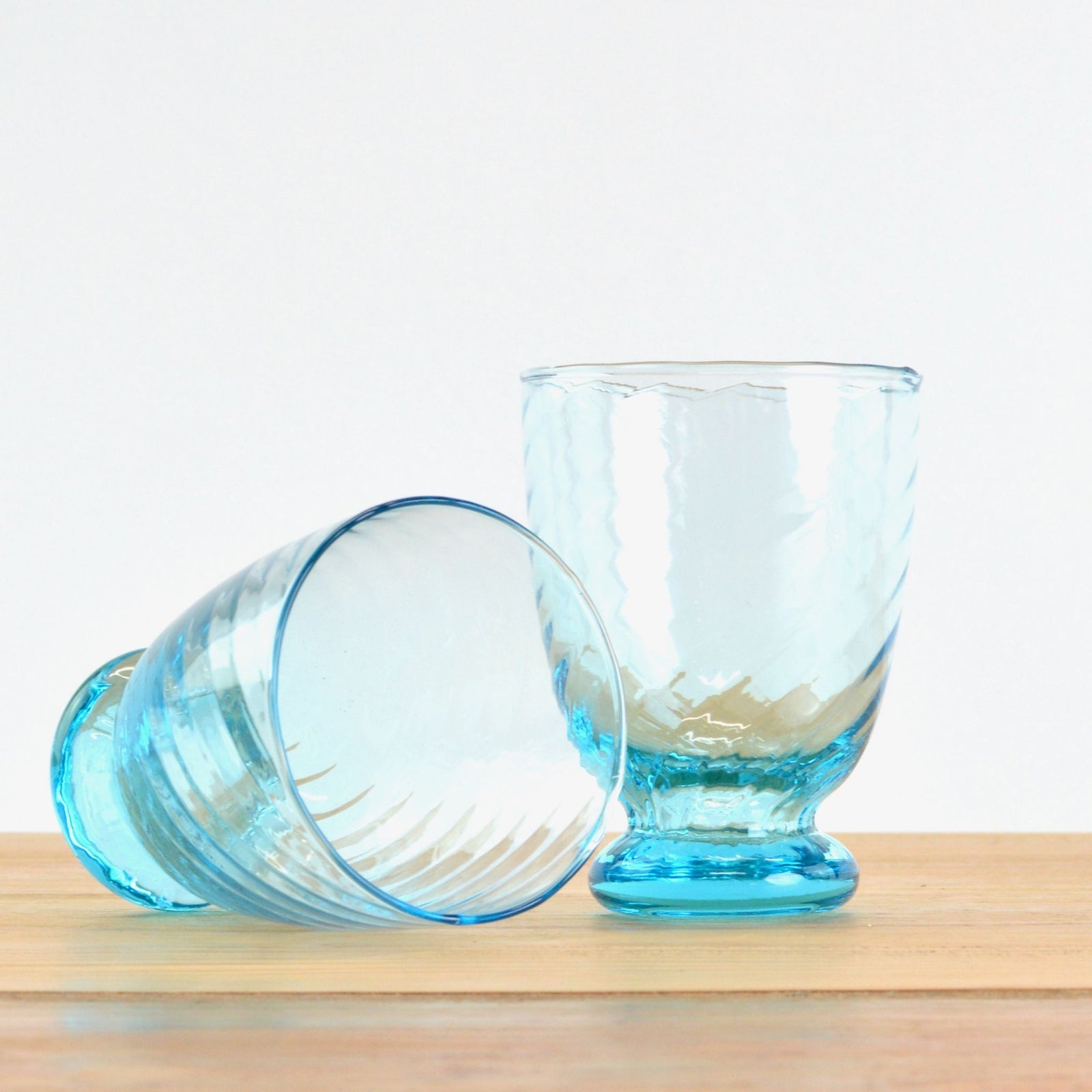 Set of two Vinci short tumblers in green, clear, and blue glass with smooth, rounded shapes for drinking and serving beverages.