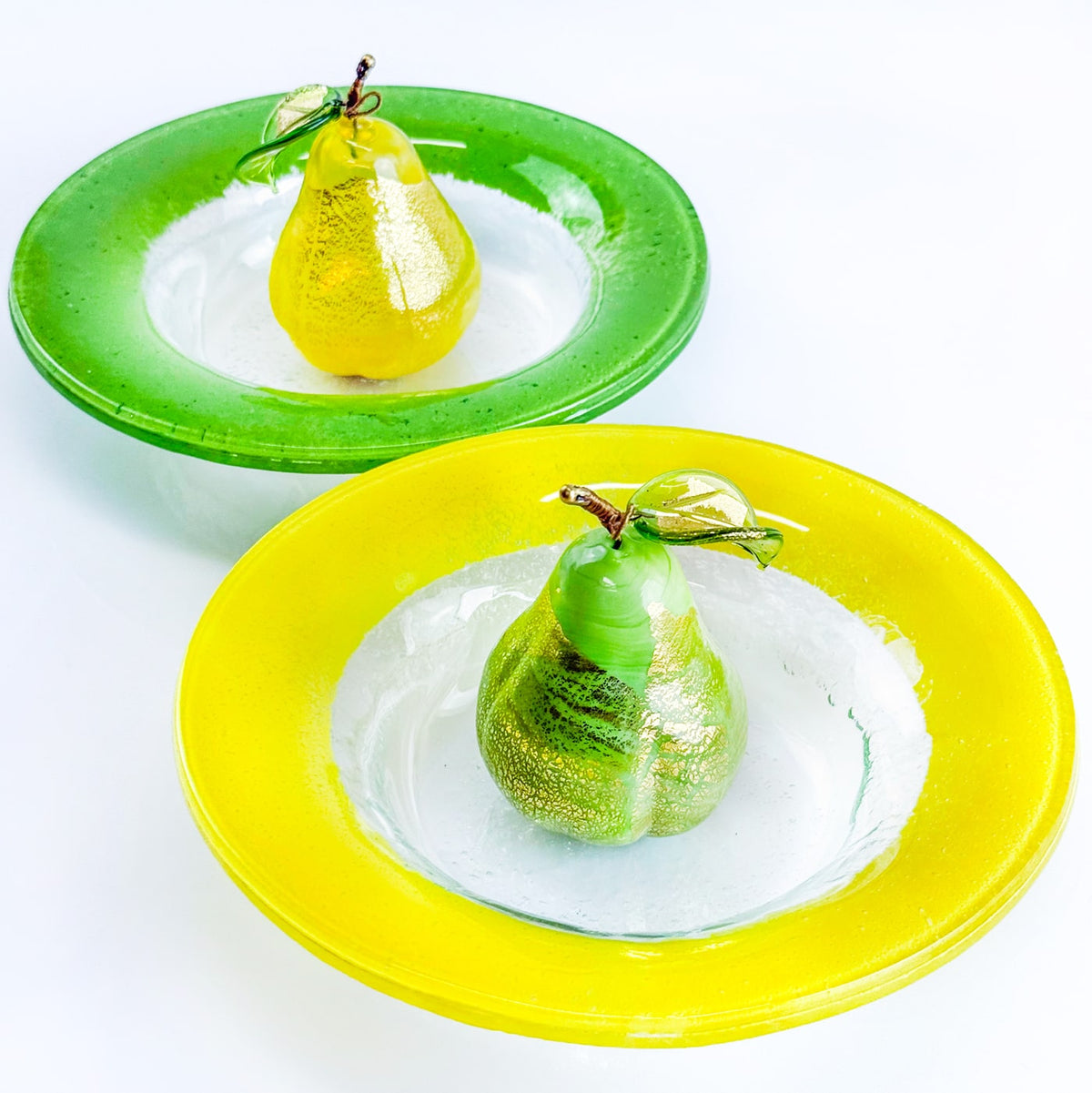 Two pears on green and yellow plates with a white background