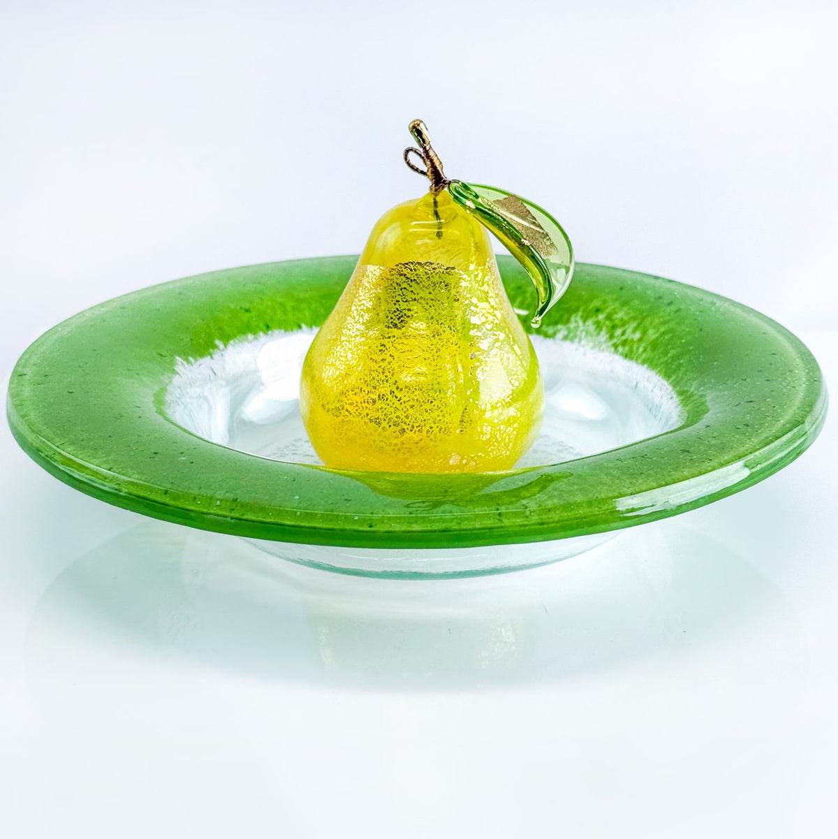 Yellow pear on a green glass plate with a white background