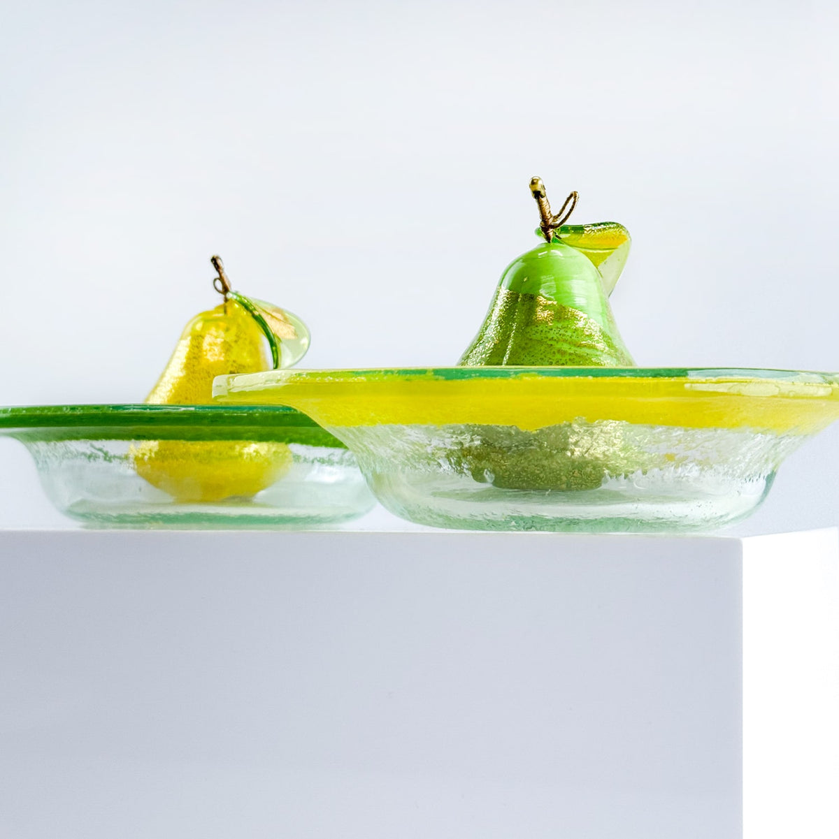 Two green pears in a glass bowl on a white background
