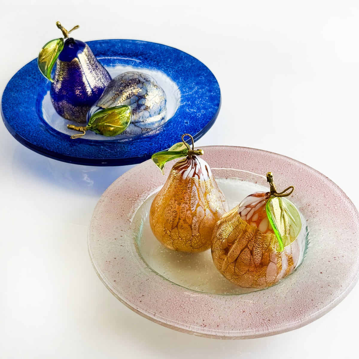 Decorative pears on glass plates with a white background