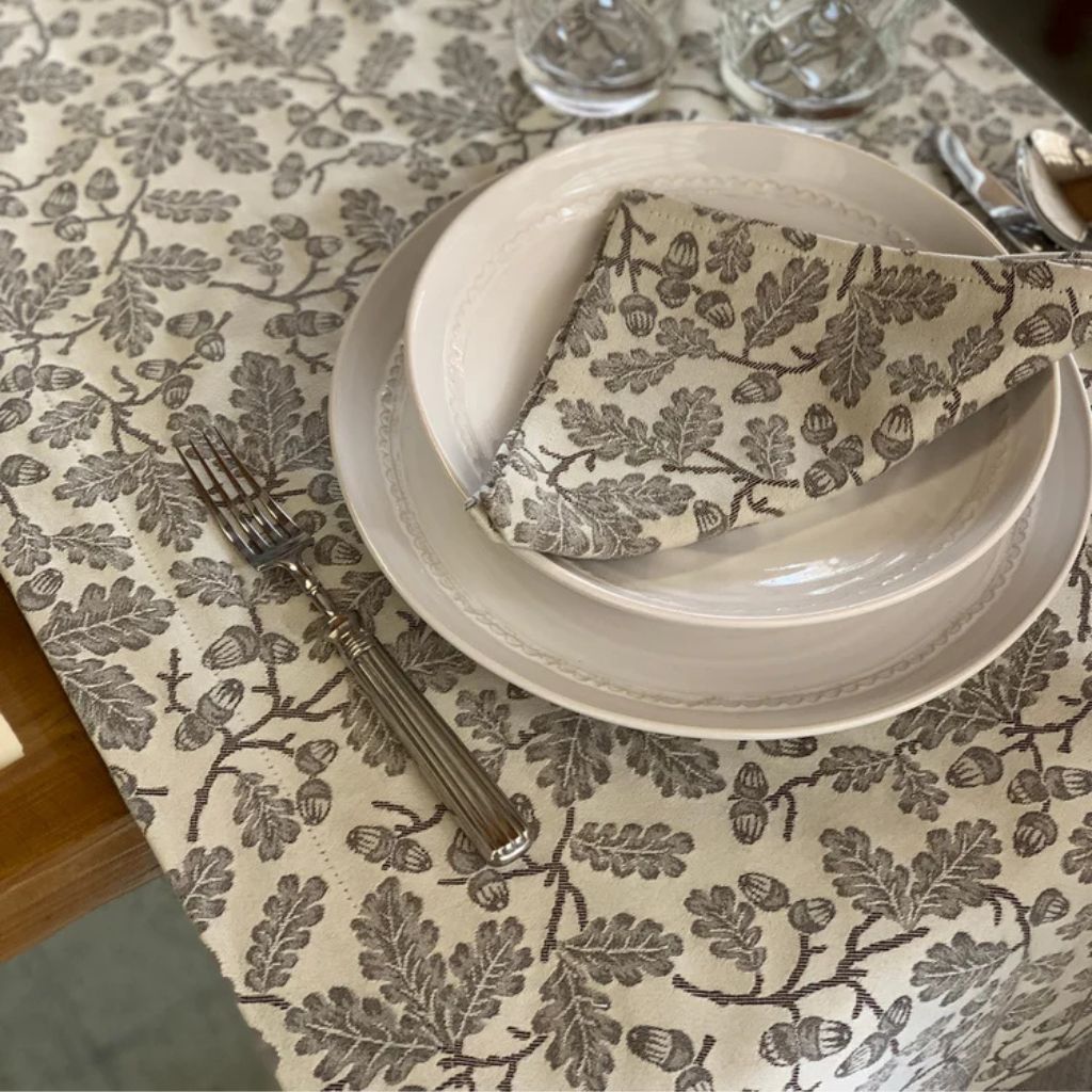 Busatti Acorn table runner from Italy, elegant linen table linen with an acorn pattern, displayed on a wooden table.