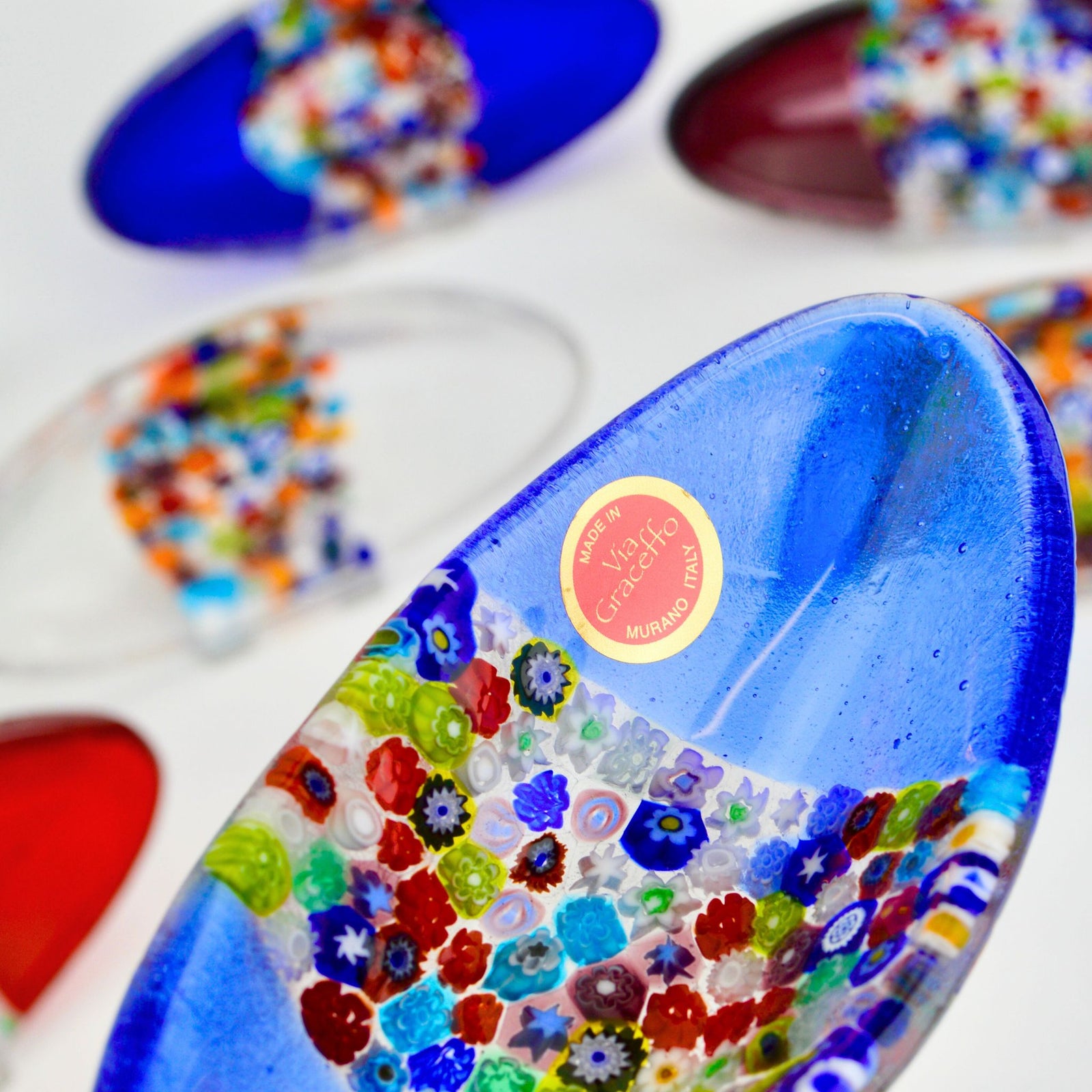 Close-up of Murano Millefiori glass oval decorative barchetta dish showing colorful, intricate patterns on a transparent tray.