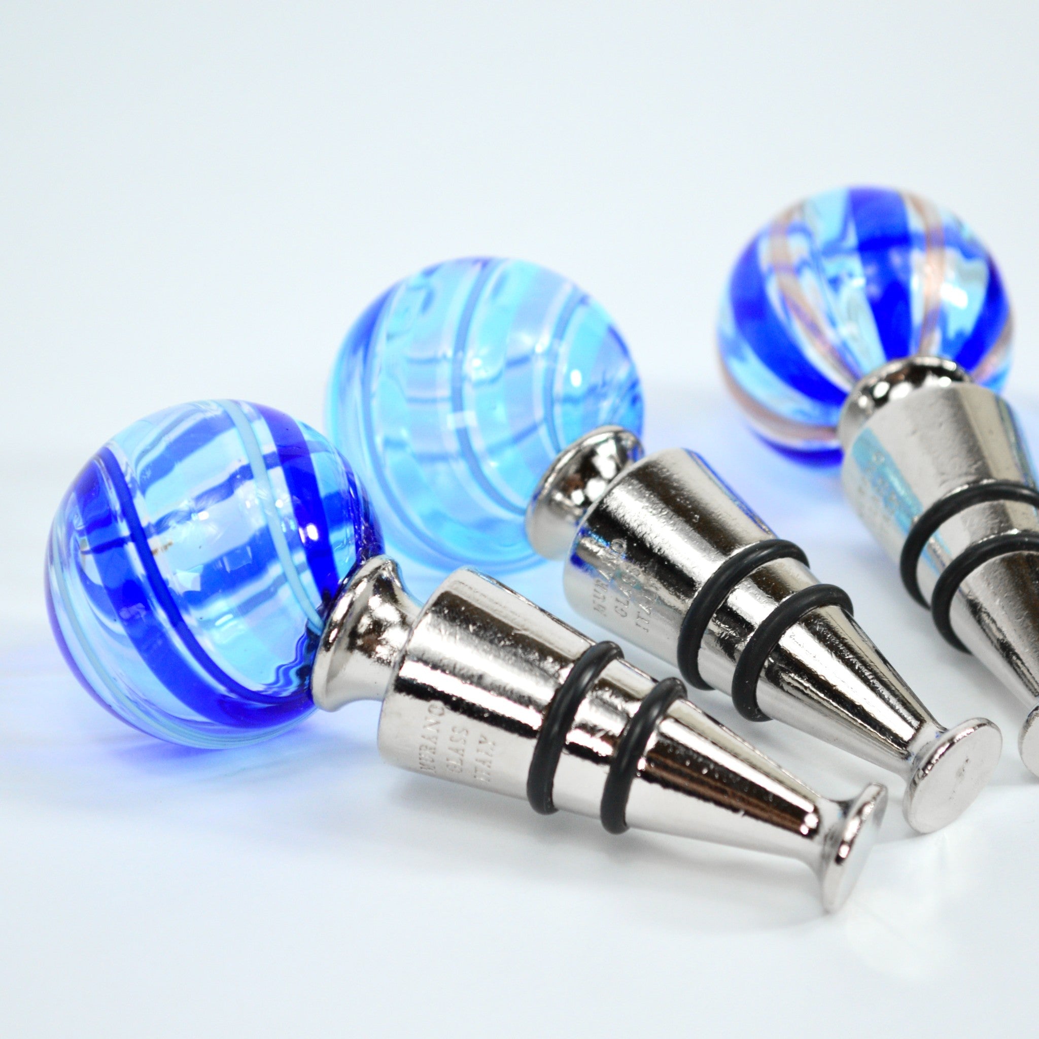 Assorted Murano glass wine stoppers in blue, made in Italy, designed to preserve wine with colorful, handcrafted glass craftsmanship.