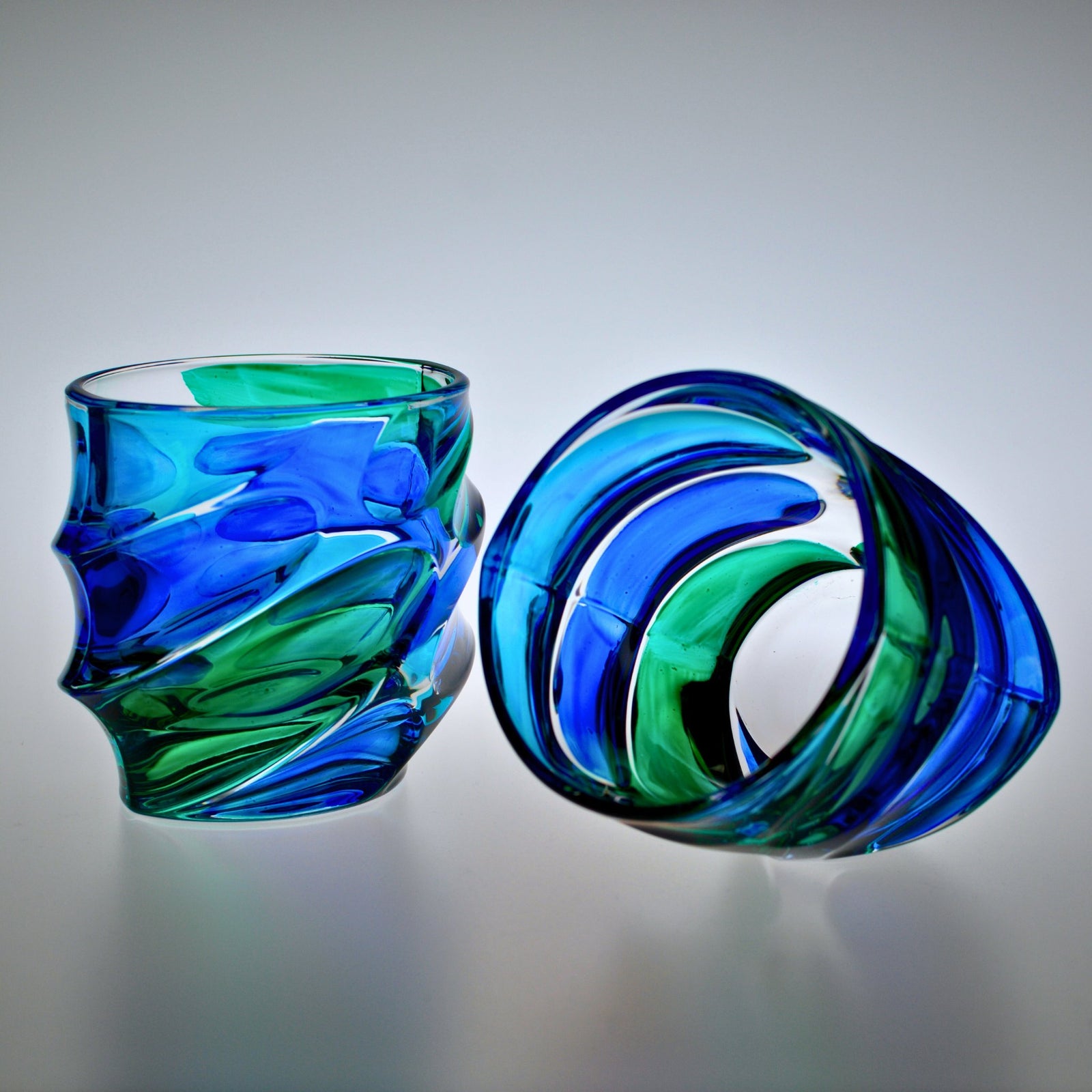 Set of two DZ Caly short drink glasses in blue and green hand-painted crystal tumblers on matte background.