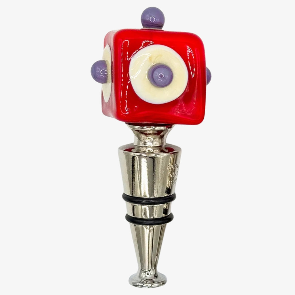 Two red glass wine bottle stoppers with silver metal bodies, one featuring a white circle with purple details and the other with green circles and purple dots, set against a plain white background.